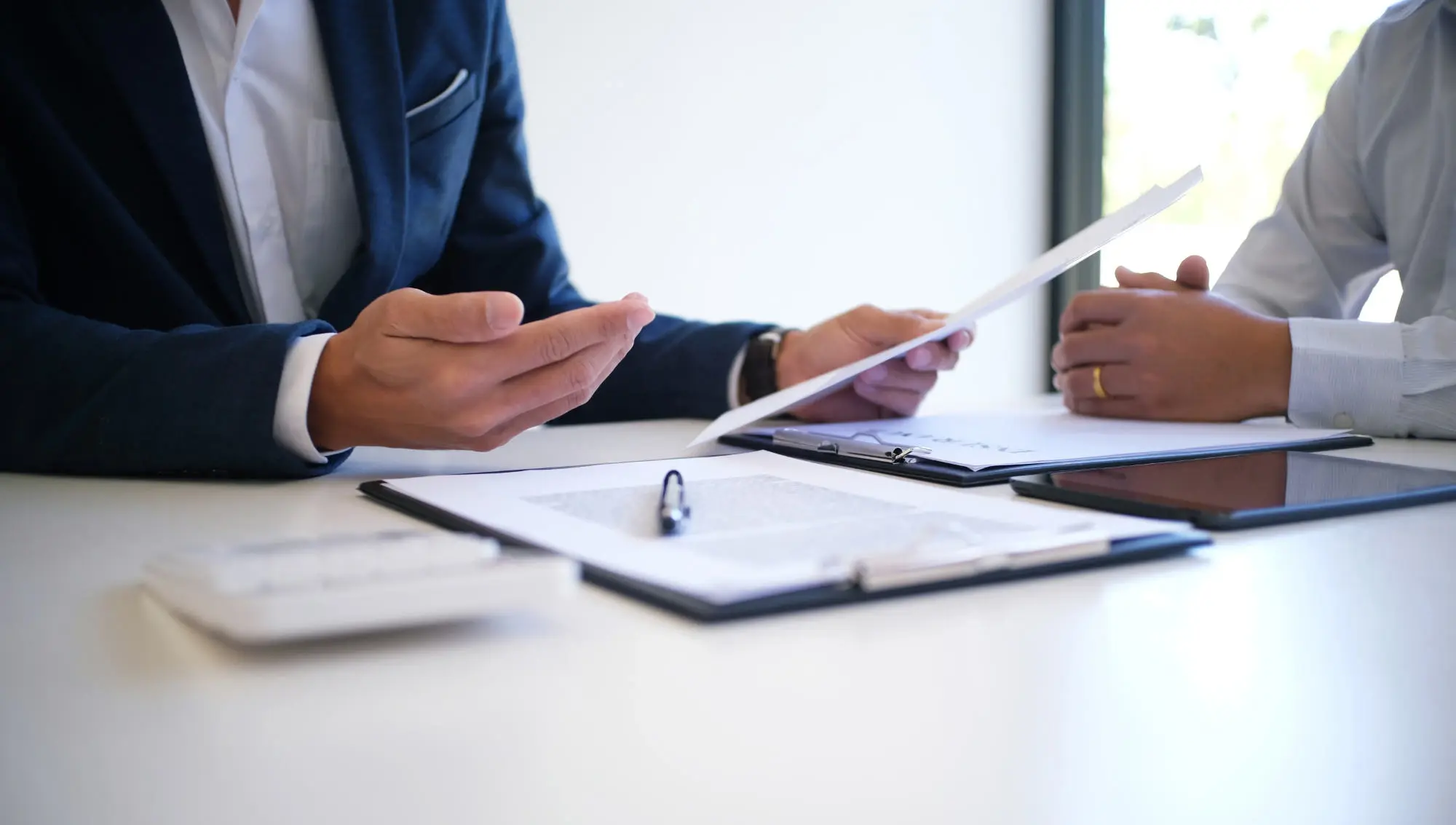 Photo of two men, sitting a table, going over a contract.